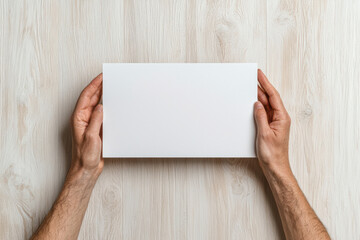 Obraz premium Caucasian male hands holding blank white paper on wooden surface