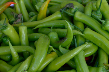 Lush green peppers piled high at a bustling outdoor market in the afternoon sun