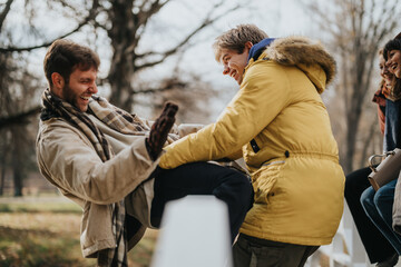 A joyful group of friends laughing and playfully interacting on an autumn day outdoors, surrounded...