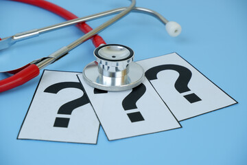 Health care and medical FAQ concept. Red stethoscope on question marks on blue background.