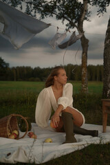A sensual woman with golden skin and full lips enjoys a countryside picnic. Her deep neckline dress...