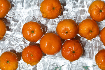 Fresh tangerines splashing into clear water top view