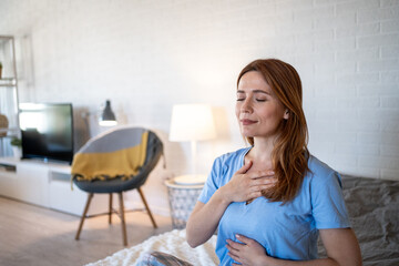 Serene woman practicing deep breathing exercise at home