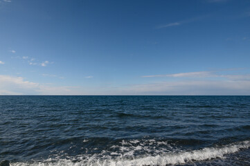 Endless blue horizon meets tranquil waves under a clear sky at midday by the coast