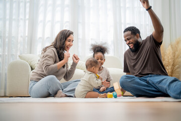 Joyful family playing together indoors while building with colorful blocks in a bright living room