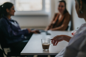 Three colleagues are having a discussion during a relaxed coffee break at work. Modern office environment with natural lighting sets the tone for collaborative brainstorming and professional