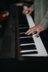 Obraz premium A close-up view of hands playing a keyboard during a music rehearsal in a studio. The image conveys focus, talent, and the atmosphere of a musical performance or practice session.