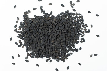 Black sesame seeds scattered on a white background macro top view