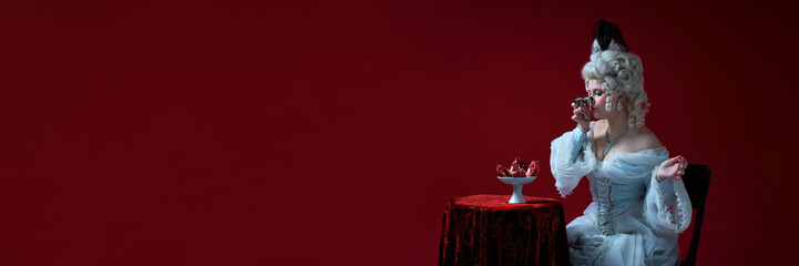 Waiting act. Lady in rococo costume playfully holding opera glasses, looking at pomegranate against...