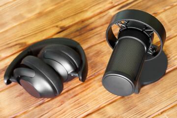 A close-up of a sleek studio microphone and modern headphones on a wooden surface, ideal for...