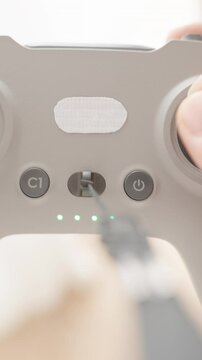 Vertical video. Hands Holding and Operating FPV Drone Joystick Controller from Overhead View in Soft Focus Light, Indoor Usage Concept