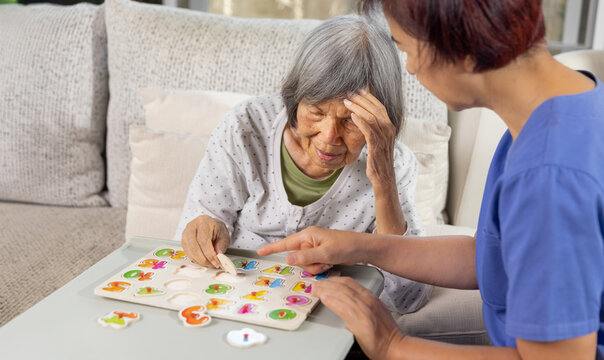 Nurse in nursing home helping a senior woman with number puzzle.  . Dementia, Alzheimer's disease concept