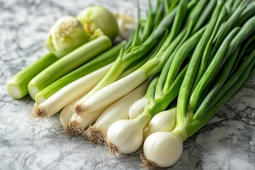 Obraz premium Fresh green onions and scallions on a marble countertop ready for cooking and garnishing dishes