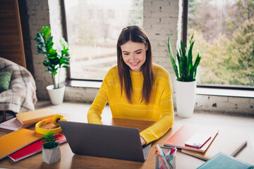 Young woman student studying with a laptop at home in a cozy, brightly lit room, elearning concept