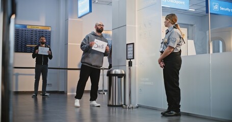 Transportation Service in International Airport Terminal: Airport Greeters Holding Name Sign, Waiting for Passengers From Plane Flight. Diverse People and Travelers Walking with Luggage. Full Shot. © Framestock