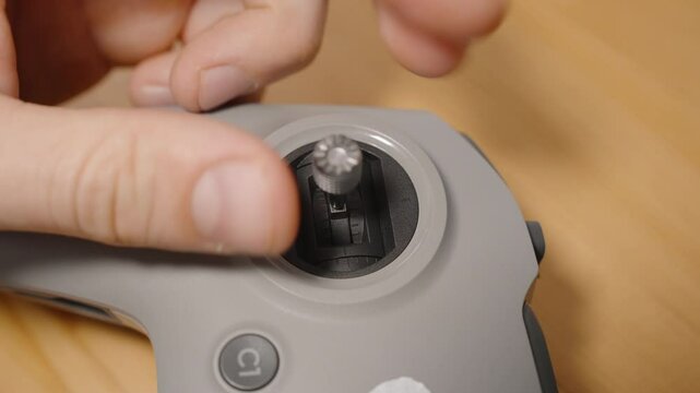 Person Screwing Metal Stick into Joystick Slot of FPV Drone Controller with Fingers in Close-Up View, Macro Perspective, Assembly Concept