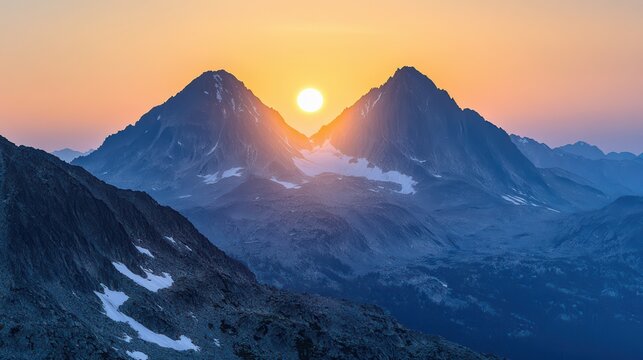 A stunning sunset illuminates twin peaks, casting golden hues over the rugged mountain landscape, creating a serene and breathtaking natural scene.