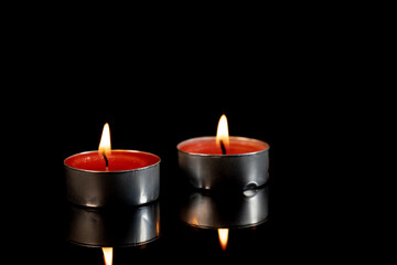 Two burning candles on black background