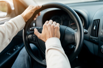 Closeup of young man honking while driving, sitting in car. Selective focus on steering wheel,...