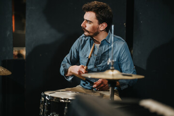 Focused musician plays the drums passionately during a rehearsal in a recording studio, preparing for a live performance. The scene captures the essence of artistic dedication and musical creativity.