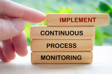 Implement Continuous Process Monitoring text on wooden blocks representing continuous Improvement Strategies