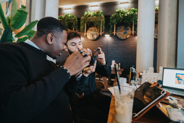 Two professional individuals working together in a coffee shop using digital devices and enjoying a friendly exchange of ideas in a collaborative atmosphere.