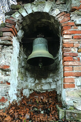 Obraz premium Old bell in weathered brick niche, fallen leaves below