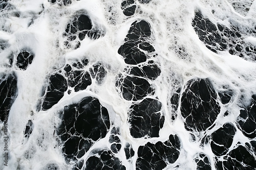 Aufkleber Ocean waves crashing against dark rocks create striking foam patterns during the day