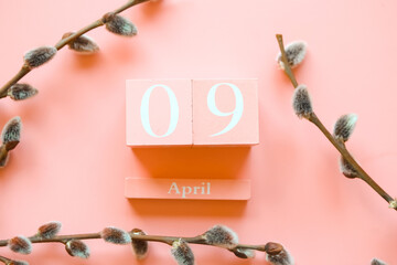 April 9. Pink cube calendar and willow branches on pink background
