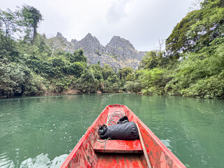 Boat exiting the Konglor Cave into lush limestone valley, Laos.