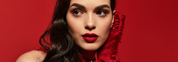 Fototapeta premium Elegant portrait of a young woman with striking red lips against a vivid backdrop