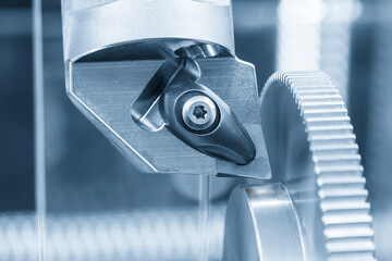Close up scene the CNC lathe machine forming cutting the metal gear parts in the light blue scene.