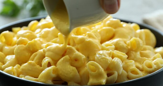 Woman pouring tasty cheese sauce onto pasta, closeup