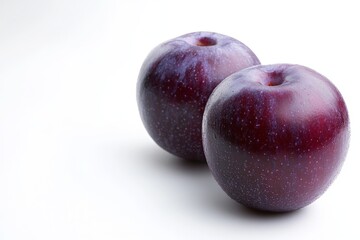 Obraz premium Fresh purple plums on a white background showcasing their smooth texture and vibrant color