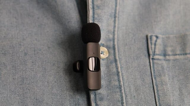 Woman putting lavalier microphone onto her shirt, closeup