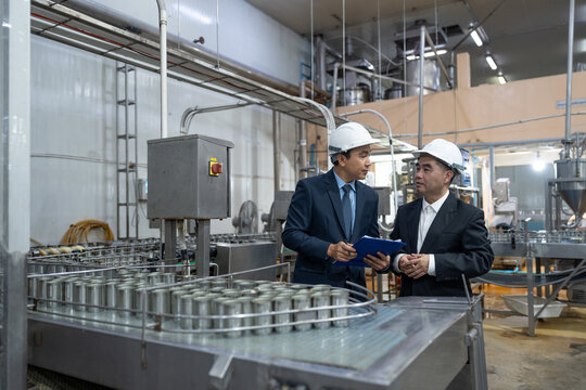 Businessman owner and partner discuss operations while inspecting food production line in canned fish factory