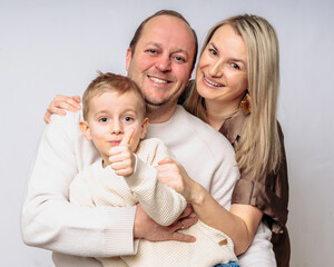 European happy family with son 4 years old, studio shot waist-high, dressed in beige colors on...