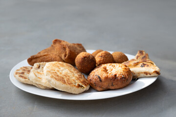 Authentic Sri Lankan different street food, short eats. Vegetable roti, Chinese Rolls , coconut roti, cutlets, mutton rolls on gray background. Snacks made with tuna, potatoes, onion and deep fried