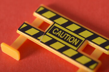 Miniature Caution Barricade Against Red Background – Safety Warning Concept