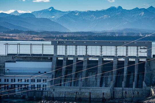 Hydro dam with power station overlooking distant Canadian Rockies near Cochrane Alberta Canada.