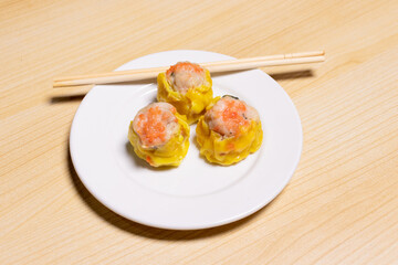 Dimsum on white plate isolated on wooden background. After edits.