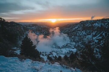 Fototapeta premium Snowy canyon landscape at sunset with mist rising in the winter sky