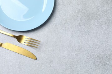 Blue empty plate with cutlery on a gray background