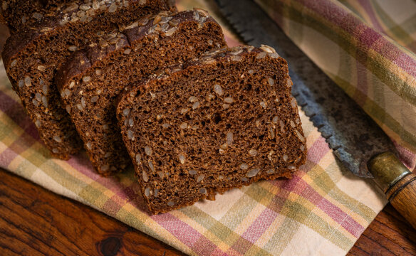 Slices of dark wholegrain rye bread with sunflower seeds and antique knife
