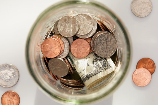 Overhead view of coins and banknotes in glass jar