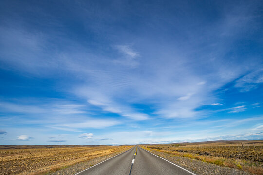 Clouds over empty road in grassy landscape