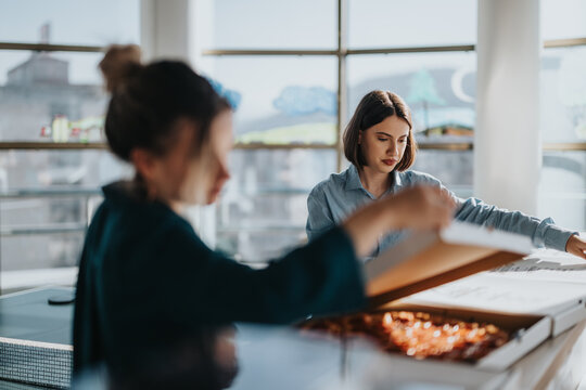Business team engages in project discussions and brainstorming in a modern office setting while sharing a pizza. Casual atmosphere enhances creativity and teamwork among young professionals.