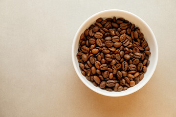 Freshly roasted coffee beans arranged in a white bowl on a light surface