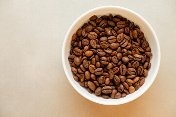 Rich brown coffee beans in a pristine white bowl against a soft backdrop