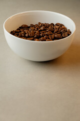 Aromatic coffee beans in a simple white bowl resting on a clean surface